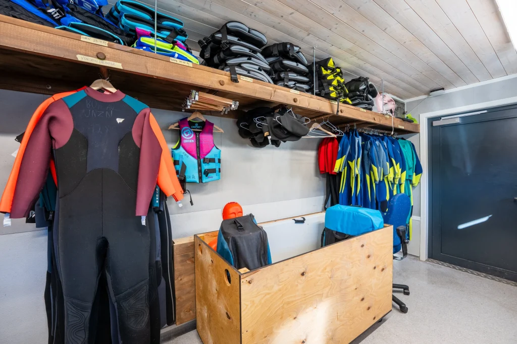 Foto av fargerike våtdrakter og svømmeføtter liggande i ei kasse inne i BUA-rommet på Oppsjø.